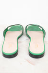 Heel view of green leather GG slides showing black heel detail and displayed against a marble surface