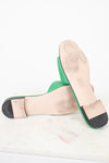 View of minimal wear to bottom soles of green slides displayed against a marble surface