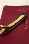 Gold clip with black resin on a Gucci branded red surface
