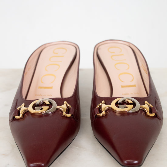 Pair of Gucci shoes with gold and silver logo on a white background