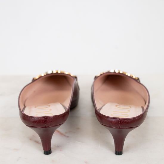 Pair of maroon kitten heel shoes on a light marble surface