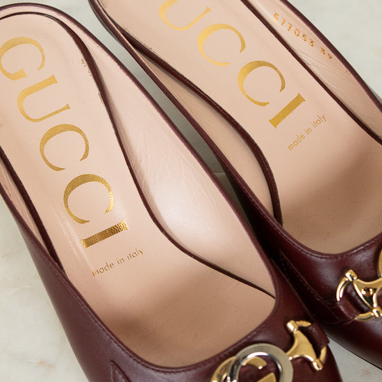 Maroon Gucci shoes with gold and silver logo on a light background