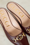 Maroon Gucci shoes with gold and silver logo on a light background