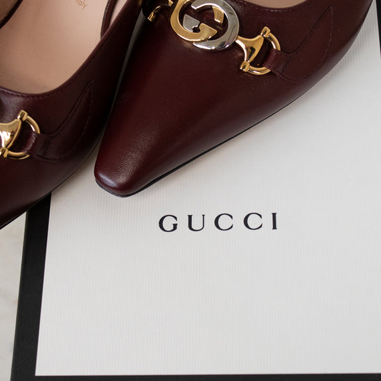 Maroon Gucci shoes with gold and silver accents on a Gucci box.
