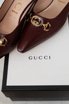 Maroon Gucci shoes with gold and silver accents on a Gucci box.