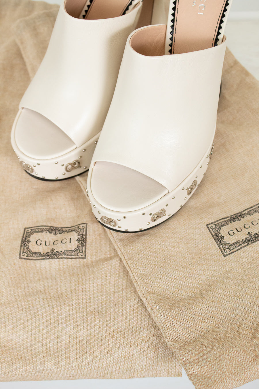 White open-toe shoes on Gucci branded dust bags