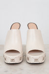 Pair of white sandals with decorative studs on a light background