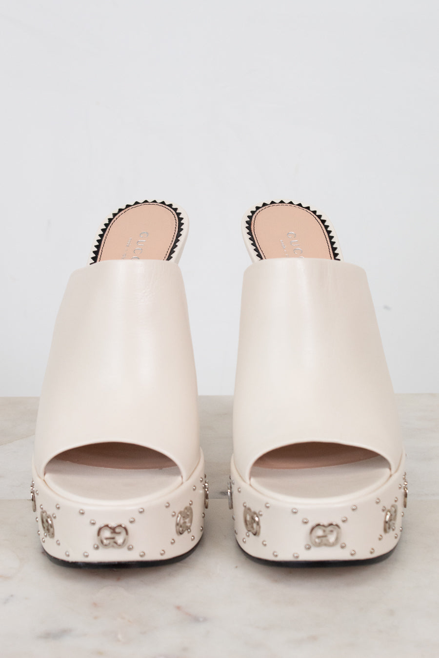Pair of white sandals with decorative studs on a light background