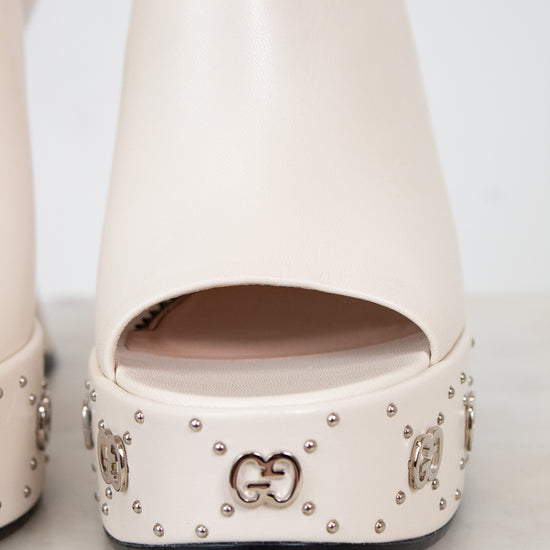 Beige high-heeled shoes with decorative studs on a white background