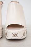 Beige high-heeled shoes with decorative studs on a white background