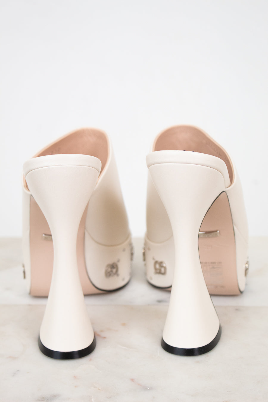 Pair of white high-heeled platform shoes on a light background