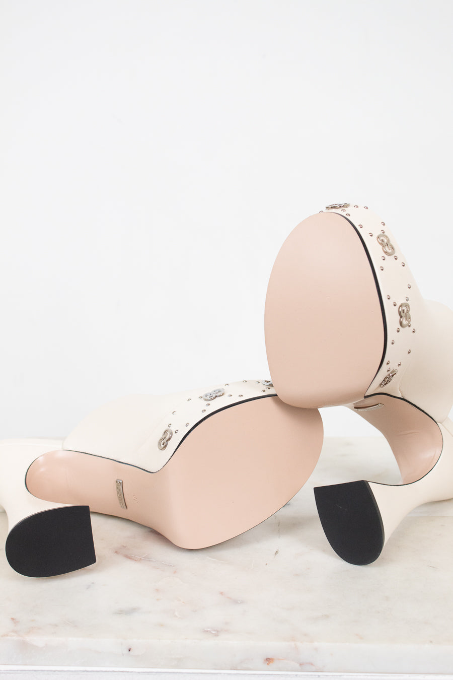 Pair of beige platform high-heeled shoes with pristine soles on a white background