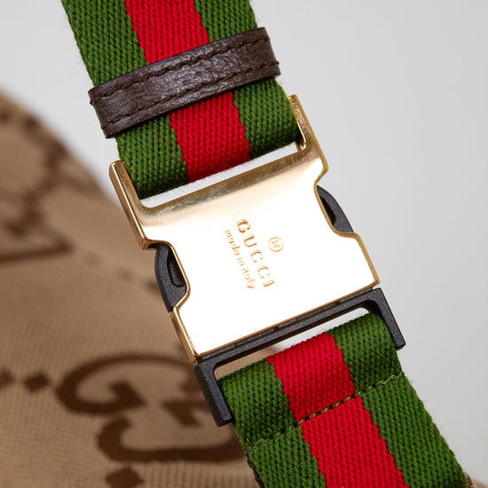 Close up of gold tone Gucci stamped buckle closure with the red and green striped straps and monogram beige bag