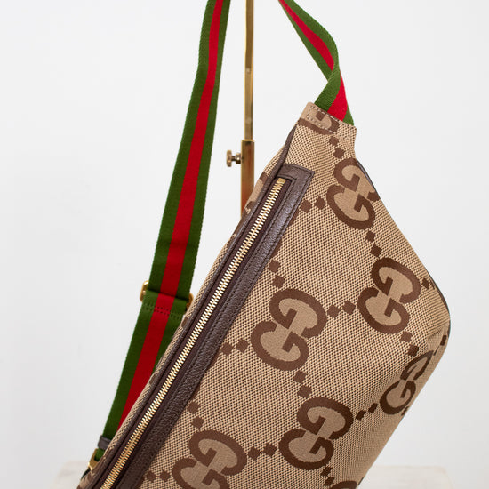 Beige belt bag with large brown gucci monogram logo with a green and red striped strap on a white background