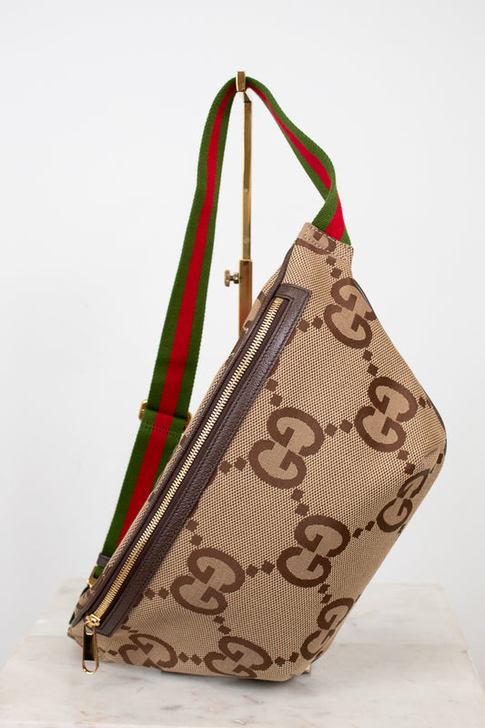 Beige belt bag with large brown gucci monogram logo with a green and red striped strap on a white background