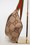 Front bottom view of beige belt bag with large brown gucci monogram logo with a green and red striped strap on a white background.