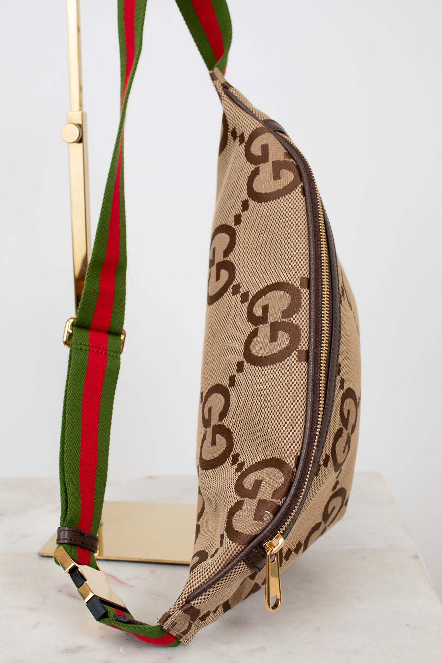 Gucci waist bag with green and red strap on a light gray background