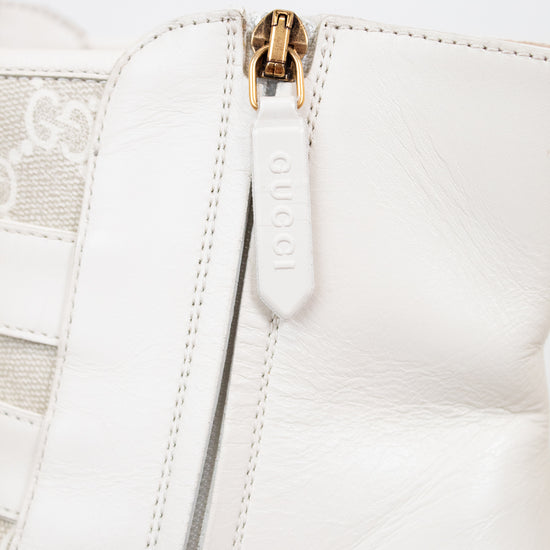 Close-up of a white leather jacket with a gold zipper on a light gray background