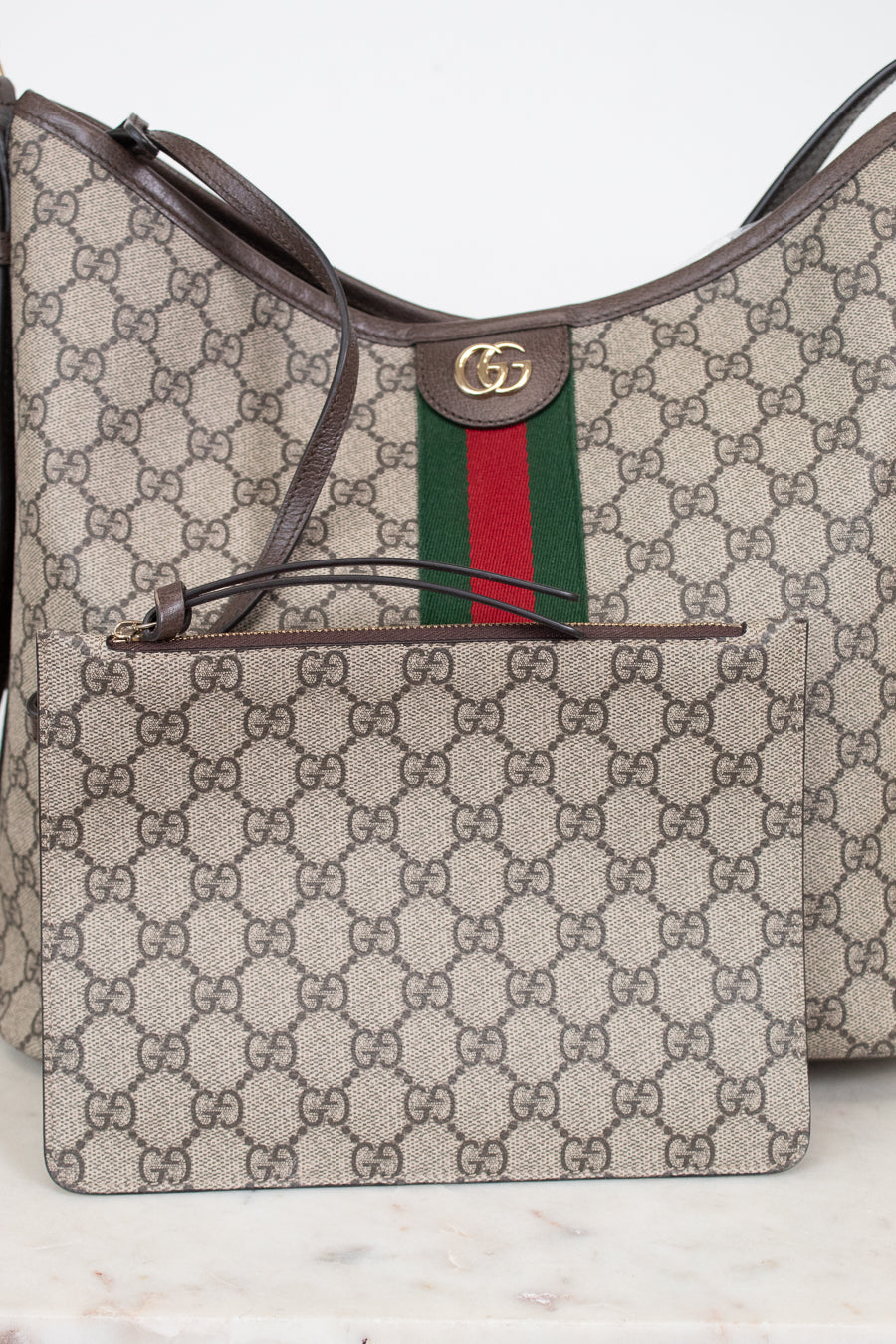 Gucci GG Supreme canvas shoulder bag with a matching zippered pouch, featuring the signature brown GG monogram, green and red web stripe, and brown leather trim.