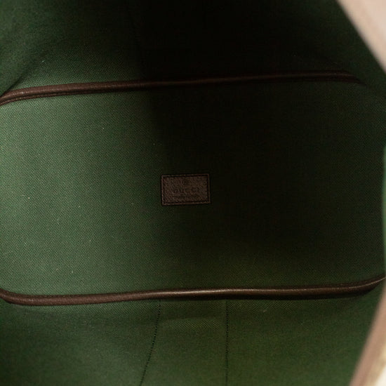 Close-up of the interior lining of a bag, showing dark green felt or fabric with brown trim and a small central brand patch.