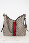 Gucci GG Supreme shoulder bag in beige with brown leather trim, a green and red web stripe down the center, and a gold-tone GG logo clasp, displayed on a white marble surface against a white background.