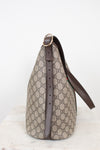A Gucci shoulder bag in beige and brown GG Supreme canvas with dark brown leather trim and strap, shown on a light marble surface against a white background.