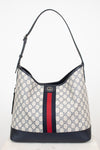 Monogrammed 'Gucci' tote bag showing red and navy center stripe with 'GG' hardware against a plain background