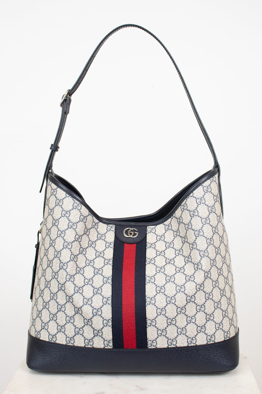 Monogrammed 'Gucci' tote bag showing red and navy center stripe with 'GG' hardware against a plain background