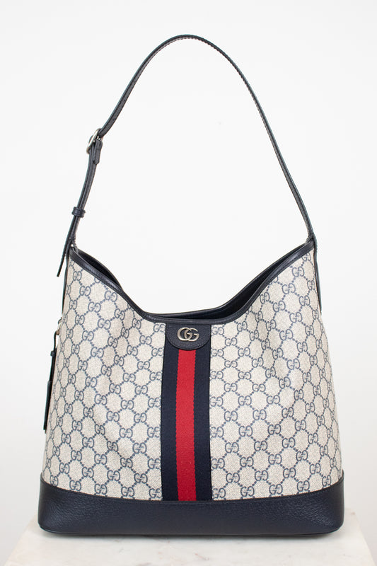 Monogrammed 'Gucci' tote bag showing red and navy center stripe with 'GG' hardware against a plain background