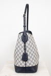 Monogrammed 'Gucci' tote bag showing  the side view with bag charm detailing against a plain background
