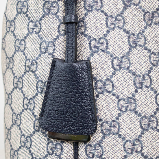 Close-up of 'GUCCI' bag charm detail shown against a GG monogrammed background