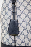 Close-up of 'GUCCI' bag charm detail shown against a GG monogrammed background