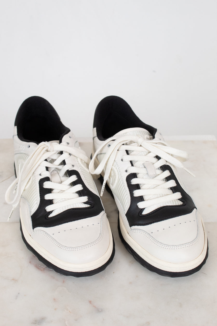White and navy sneakers set against  plain marble surface