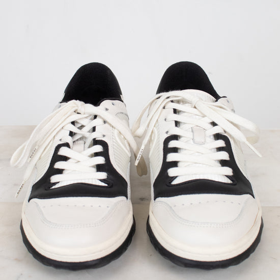 Rounded toe view of white and navy sneakers against a marble surface