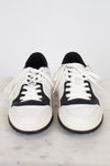 Rounded toe view of white and navy sneakers against a marble surface