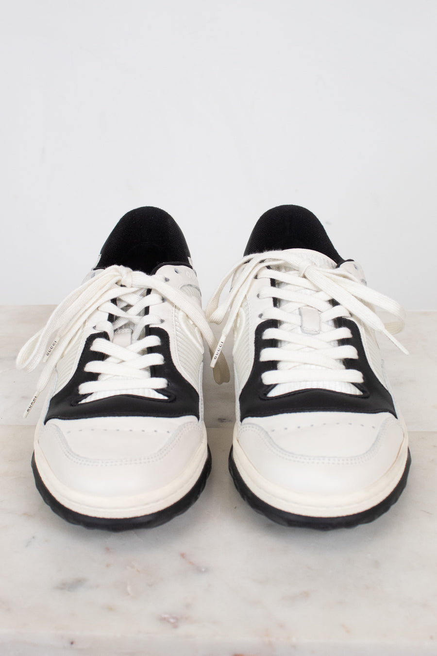 Rounded toe view of white and navy sneakers against a marble surface