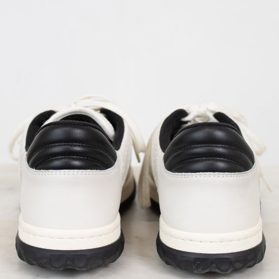 Heel view of white and navy sneakers against a plain marble background