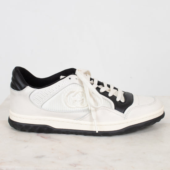 Side view of white and navy sneakers set against a marble and plain background