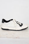 Side view of white and navy sneakers set against a marble and plain background