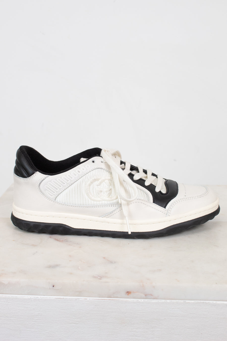Side view of white and navy sneakers set against a marble and plain background