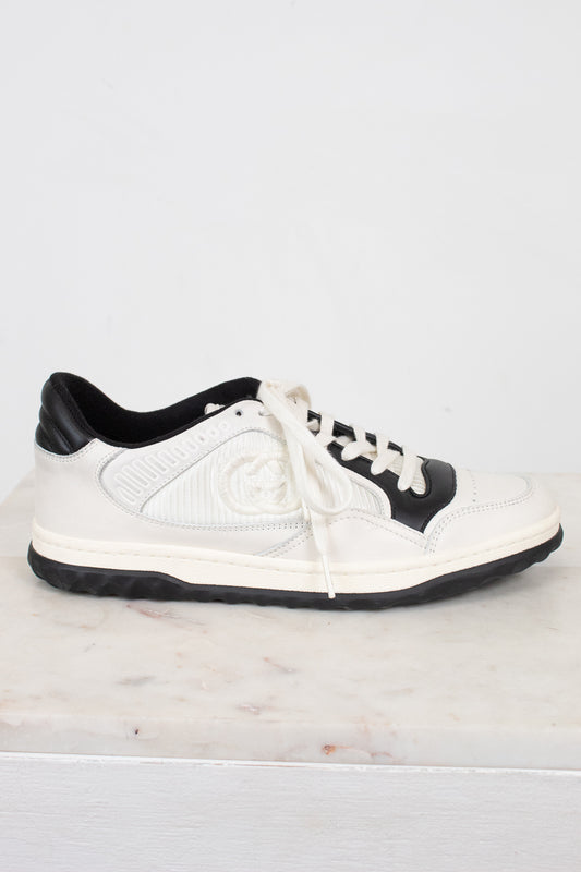Side view of white and navy sneakers set against a marble and plain background