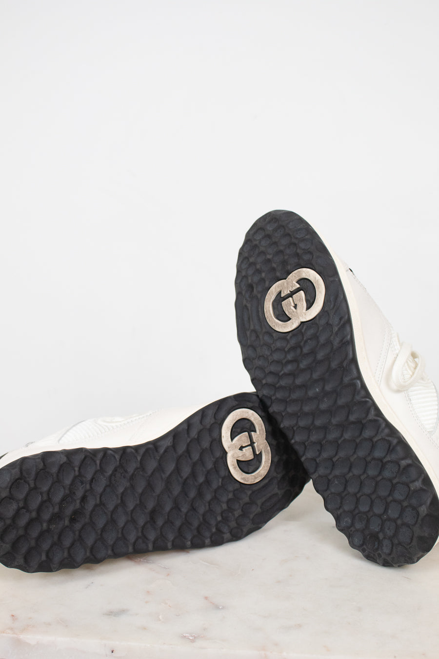 Bottom view of exterior soles showing minimal wear to navy and white 'GG' logo sneakers