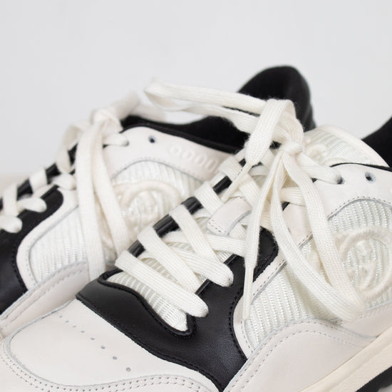 Close-up of laces of white and navy sneakers set against a plain background