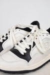 Close-up of laces of white and navy sneakers set against a plain background