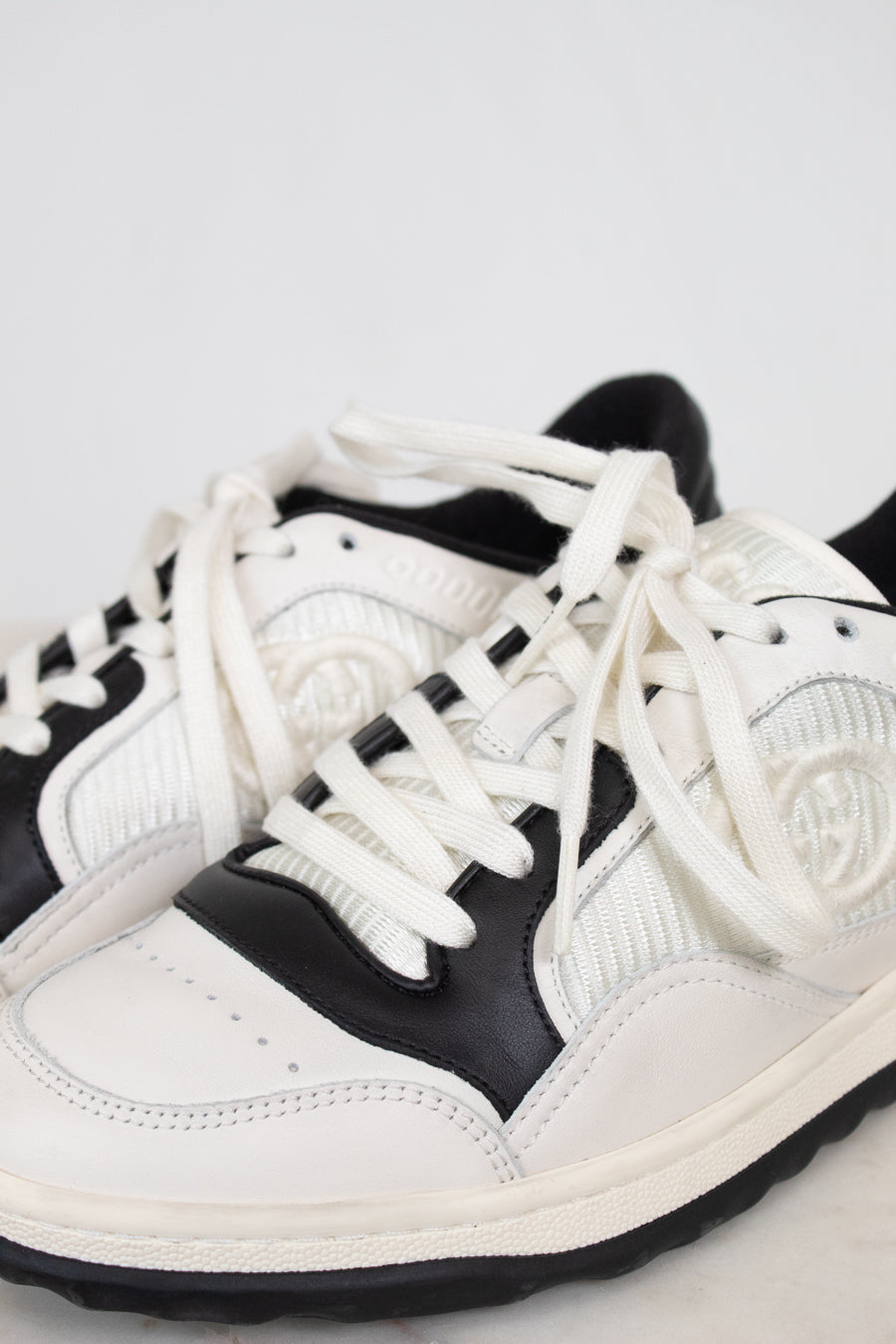 Close-up of laces of white and navy sneakers set against a plain background