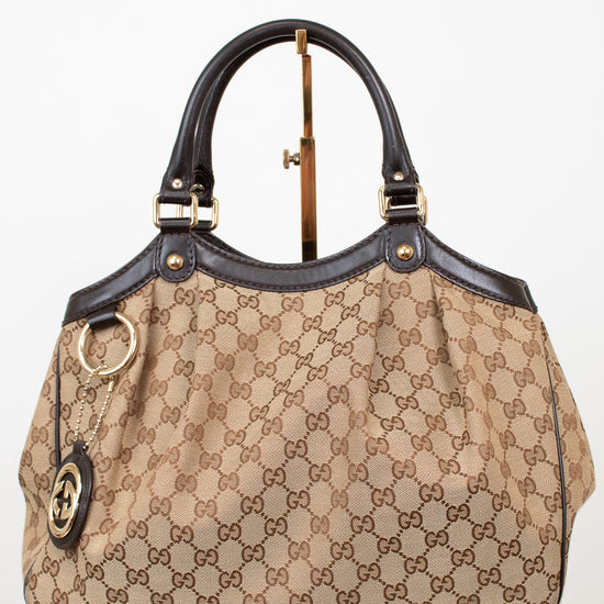 Beige handbag with brown Gucci monogram print on a white background