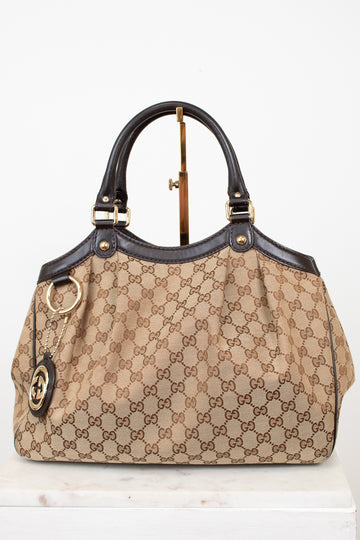 Beige handbag with brown Gucci monogram print on a white background