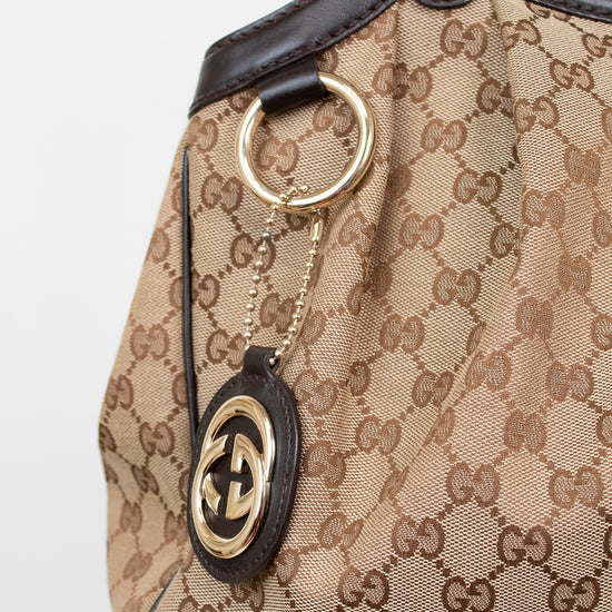 Close-up of a Gucci handbag with monogram pattern and keychain.