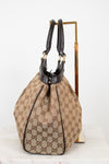 Side view of beige handbag with brown Gucci monogram with brown handles on a white background
