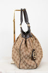 Side view of beige handbag with brown Gucci monogram with brown handles on a white background